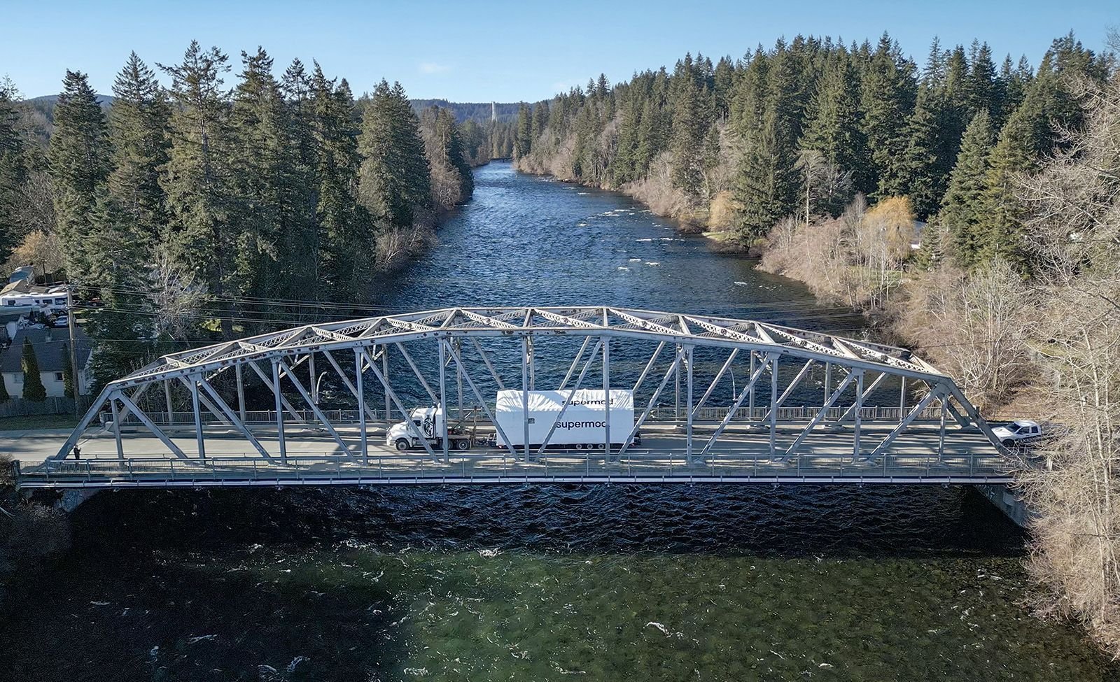 Module crossing a steel truss bridge on its way to site