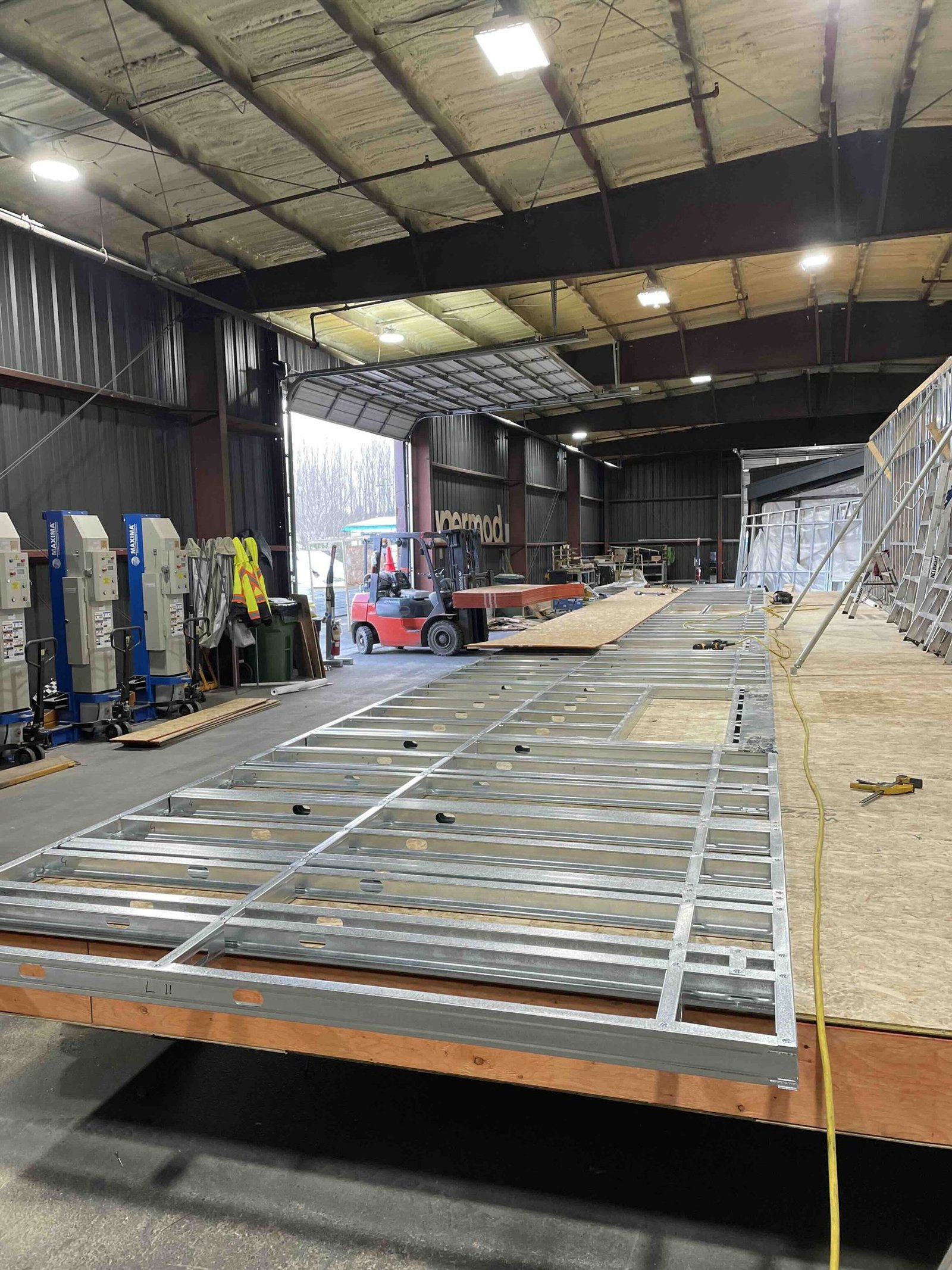 Light-gauge steel floor panel being framed in a production building
